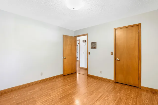 a view of an empty room with wooden floor and closet