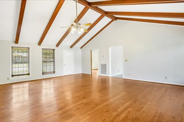 a view of an empty room with wooden floor and windows