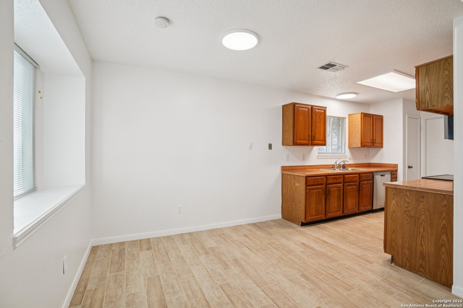 1012 Dimrock Schertz, TX 78154 - Photo 5 of 20 a large white kitchen with a sink and dishwasher a stove top oven with wooden floor