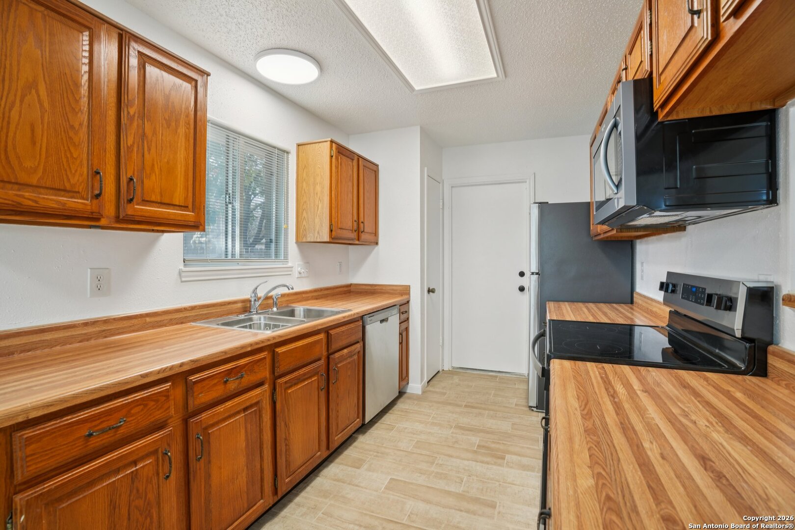 1012 Dimrock Schertz, TX 78154 - Photo 7 of 20 a kitchen with stainless steel appliances a sink dishwasher a stove top oven a refrigerator with wooden cabinets and floor