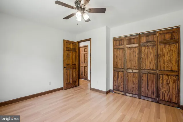 an empty room with wooden floor closet chandelier fan and windows