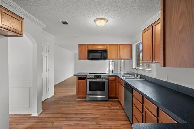 a kitchen with stainless steel appliances granite countertop a stove a sink and a microwave