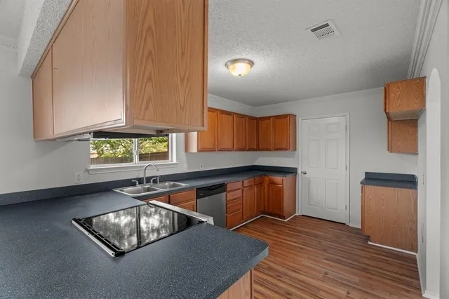 a kitchen with stainless steel appliances granite countertop a sink dishwasher stove and cabinets with wooden floor