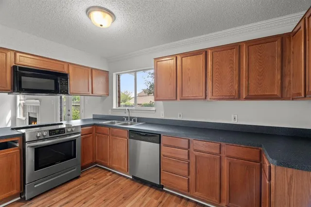 a kitchen with granite countertop wooden cabinets stainless steel appliances and a window