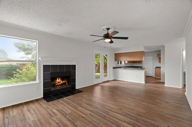 a view of an empty room with wooden floor fireplace and a window
