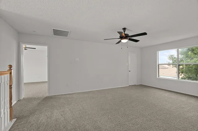 an empty room with a window and a ceiling fan