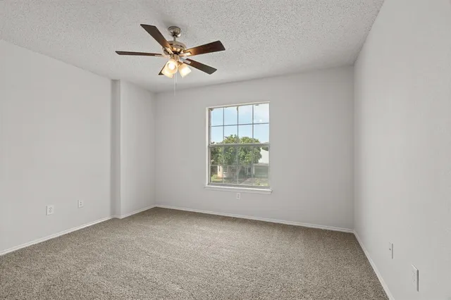 an empty room with a window and a ceiling fan
