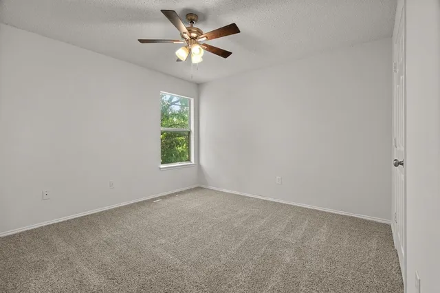 an empty room with windows and fan