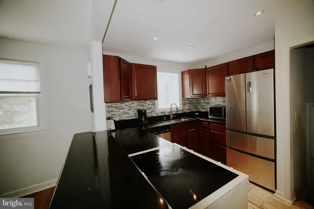 a kitchen with stainless steel appliances granite countertop a refrigerator a sink a stove a microwave and a counter space