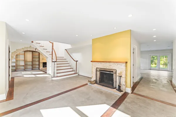 a view of a livingroom with a fireplace a ceiling fan and windows