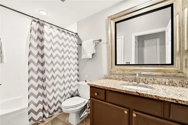 a bathroom with a granite countertop sink a toilet and a mirror