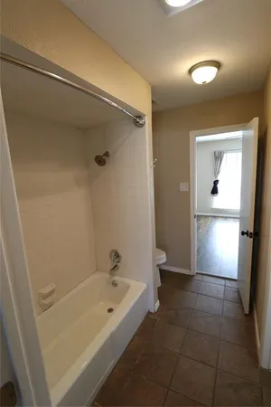a bathroom with a tub shower and toilet