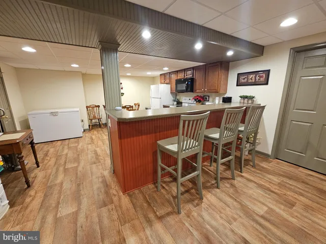 a open kitchen with stainless steel appliances granite countertop a table chairs and a wooden floors