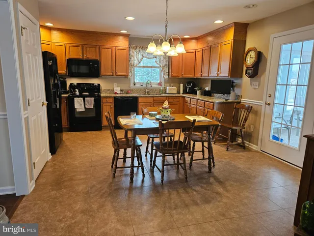 a kitchen with stainless steel appliances kitchen island granite countertop a refrigerator a stove a sink a dining table and chairs with wooden floor