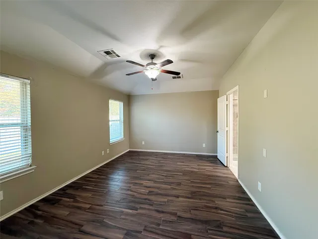 a view of an empty room with window and wooden floor