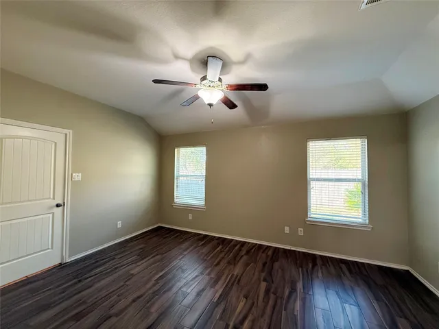 an empty room with wooden floor chandelier fan and windows