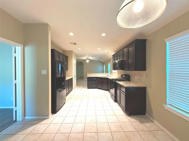 a large kitchen with stainless steel appliances kitchen island granite countertop a refrigerator and a sink