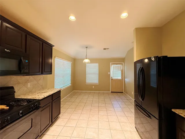 a kitchen with granite countertop a refrigerator and a stove top oven