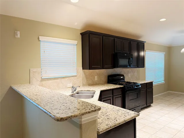 a kitchen with granite countertop a sink and a stove top oven with wooden floor