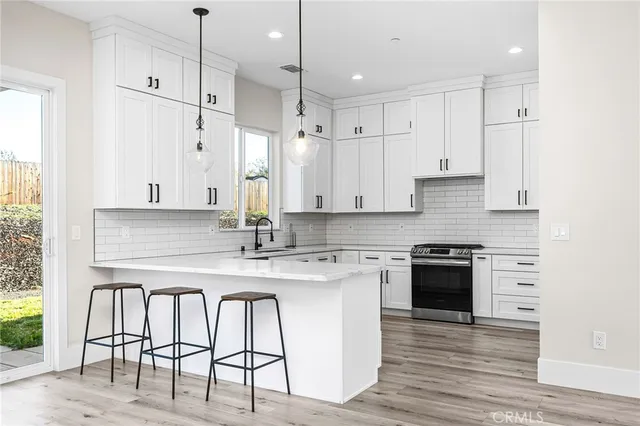 a kitchen with stainless steel appliances granite countertop a stove a sink a refrigerator and white cabinets