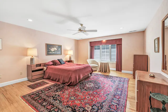 a spacious bedroom with a bed and wooden floor