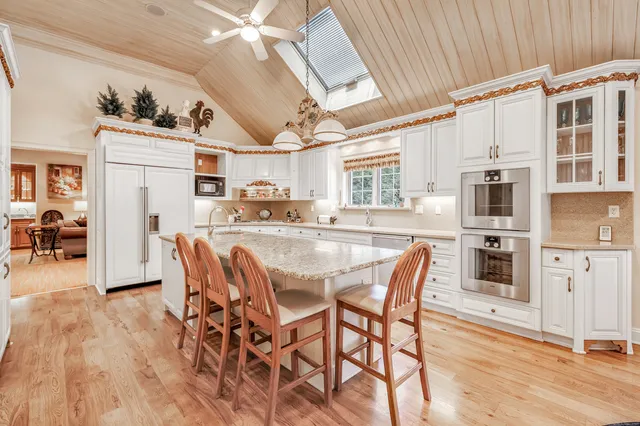 a dining room with stainless steel appliances kitchen island granite countertop a table chairs and a refrigerator