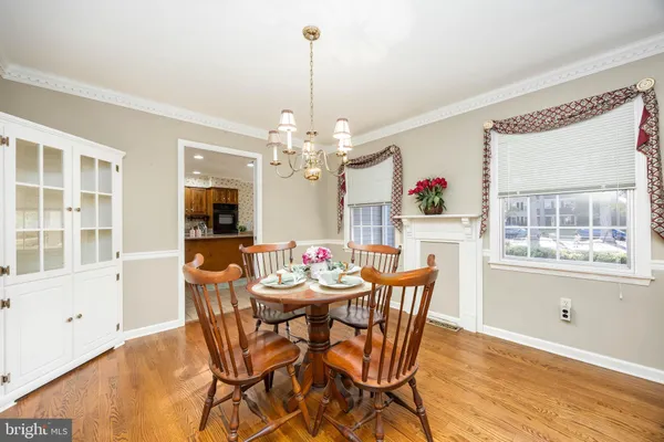 a kitchen with stainless steel appliances granite countertop a refrigerator a stove a sink a dining table and chairs with wooden floor