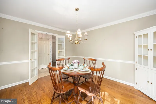a dining room with wooden floor a chandelier a wooden table and chairs