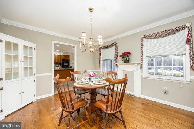 a kitchen with stainless steel appliances granite countertop a refrigerator a stove a sink a dining table and chairs with wooden floor