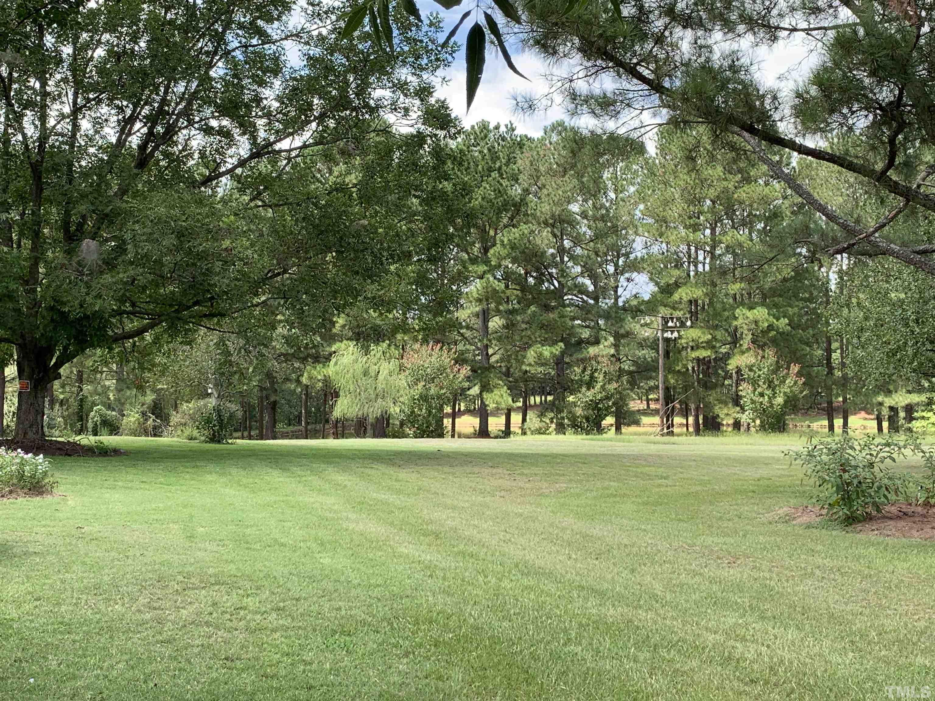9832 Sauls Road Raleigh, NC 27603 - Photo 13 of 16 a view of a grassy field with trees