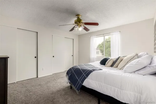 a bedroom with a bed ceiling fan and a window