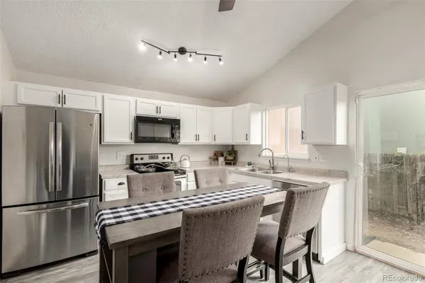 a kitchen with kitchen island granite countertop a refrigerator a stove a sink cabinets and a dining table
