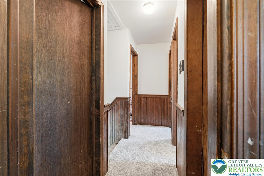 1385 Woodmere Road Pottstown, PA 19464 - Photo 23 of 57 A well-maintained hallway with warm wood paneling, featuring light-colored carpeting and inviting doorways.