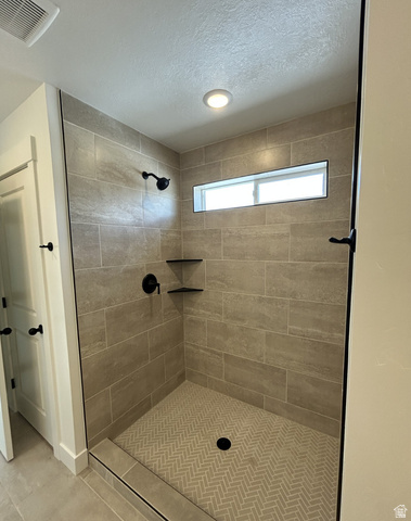 1213 West 500 South Logan, UT 84321 - Photo 30 of 32 Walk-in shower featuring light-toned large format wall tiling, a herringbone pattern floor, matte black shower fixtures, two built-in corner shelves, and a horizontal window