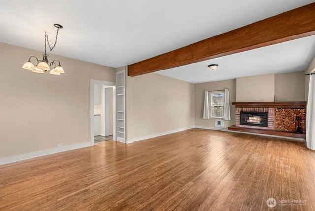 a view of a livingroom with a fireplace a window and wooden floor