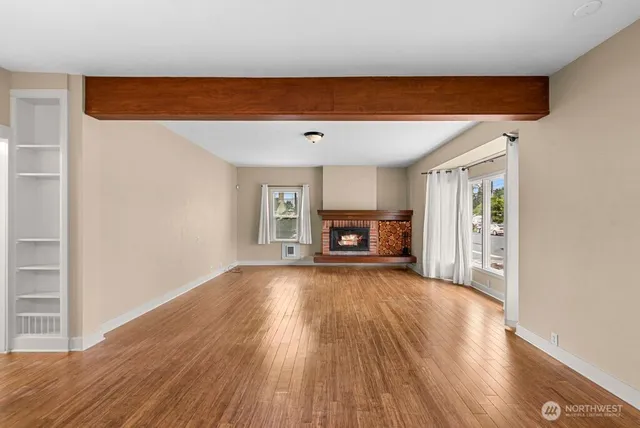 a view of empty room with wooden floor and fireplace