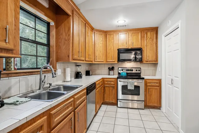 a kitchen with stainless steel appliances granite countertop a stove a sink and a microwave