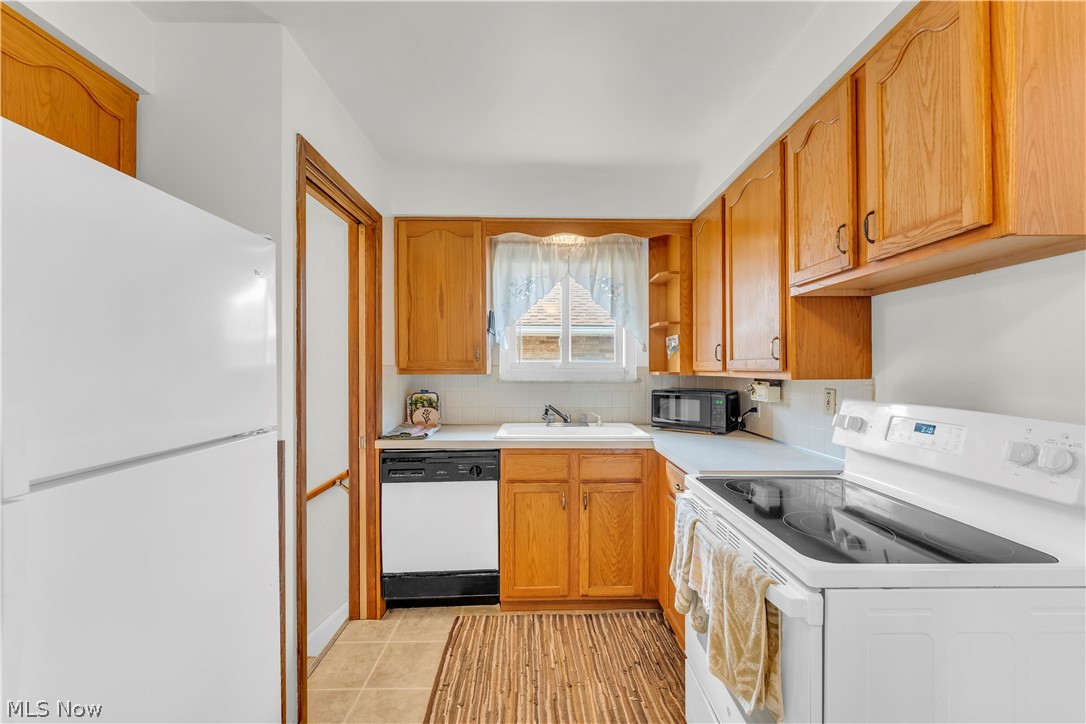 3023 Norris Avenue Cleveland, OH 44134 - Photo 13 of 41 Bright kitchen featuring wood cabinetry, white countertops, a white electric range, a white refrigerator, and a built-in dishwasher
