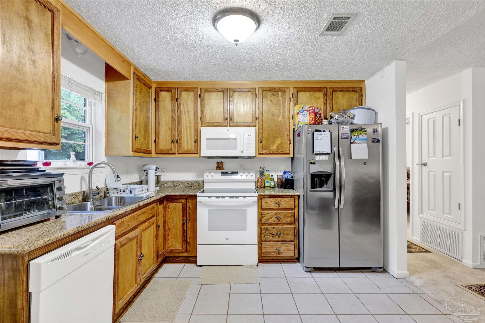 5131 Oakleaf Drive Pace, FL 32571 - Photo 7 of 23 a kitchen with stainless steel appliances granite countertop a refrigerator and a sink