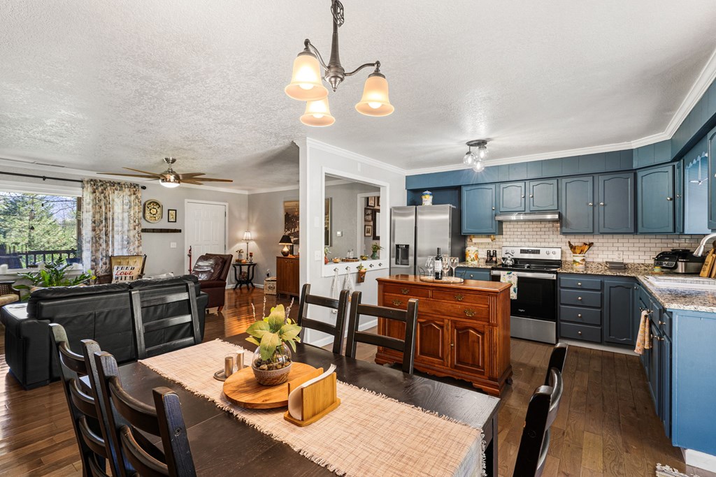 496 Jackie Cove Road Hayesville, NC 28904 - Photo 5 of 41 a kitchen with stainless steel appliances granite countertop a stove top oven a refrigerator a sink dishwasher a dining table and chairs with wooden floor