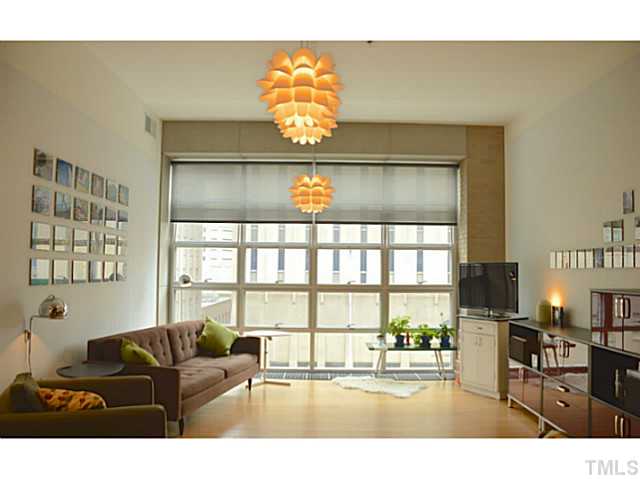 Living room has bamboo floors and a wall of windows overlooking Fayetteville Street.