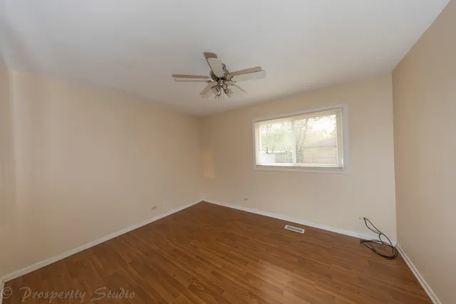 a view of a room with wooden floor and a ceiling fan