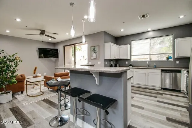 a kitchen with stainless steel appliances granite countertop a sink a stove a refrigerator cabinets and a dining table