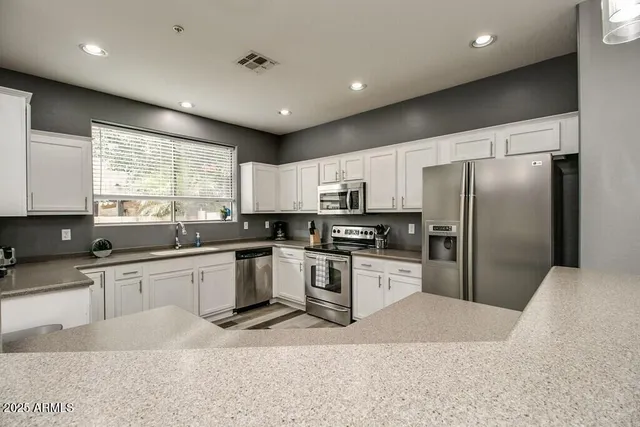 a kitchen with stainless steel appliances kitchen island granite countertop a refrigerator sink and cabinets