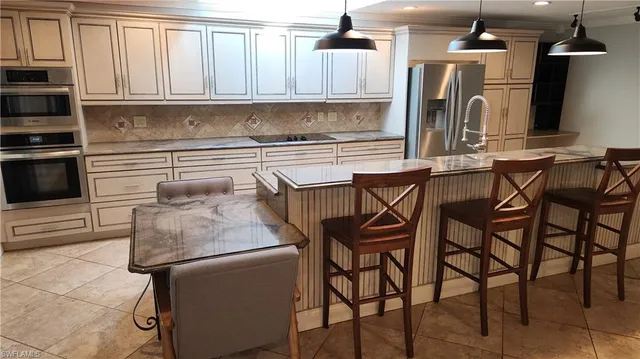 a kitchen with stainless steel appliances kitchen island granite countertop a table chairs in it and wooden floors