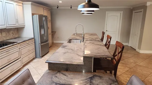 a kitchen with stainless steel appliances kitchen island granite countertop a refrigerator a stove and a sink with wooden floor