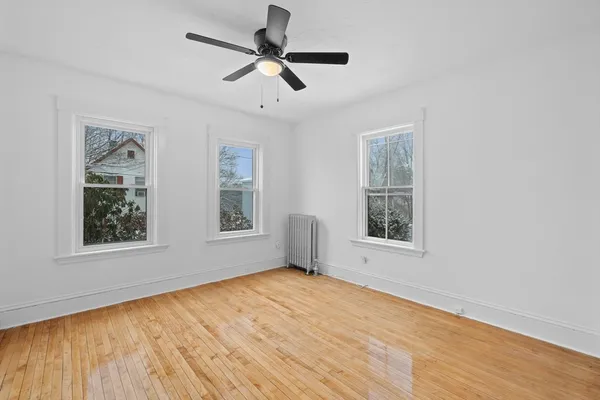 a view of an empty room with a window and wooden floor