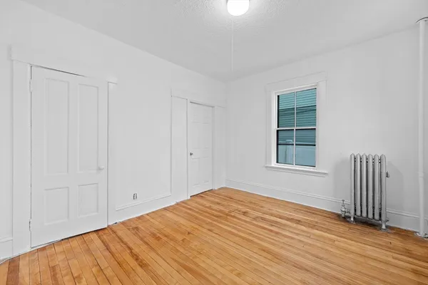 a view of empty room with wooden floor and windows
