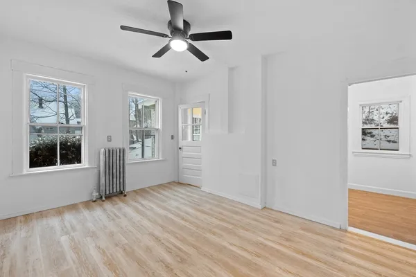 a view of an empty room with a window and wooden floor