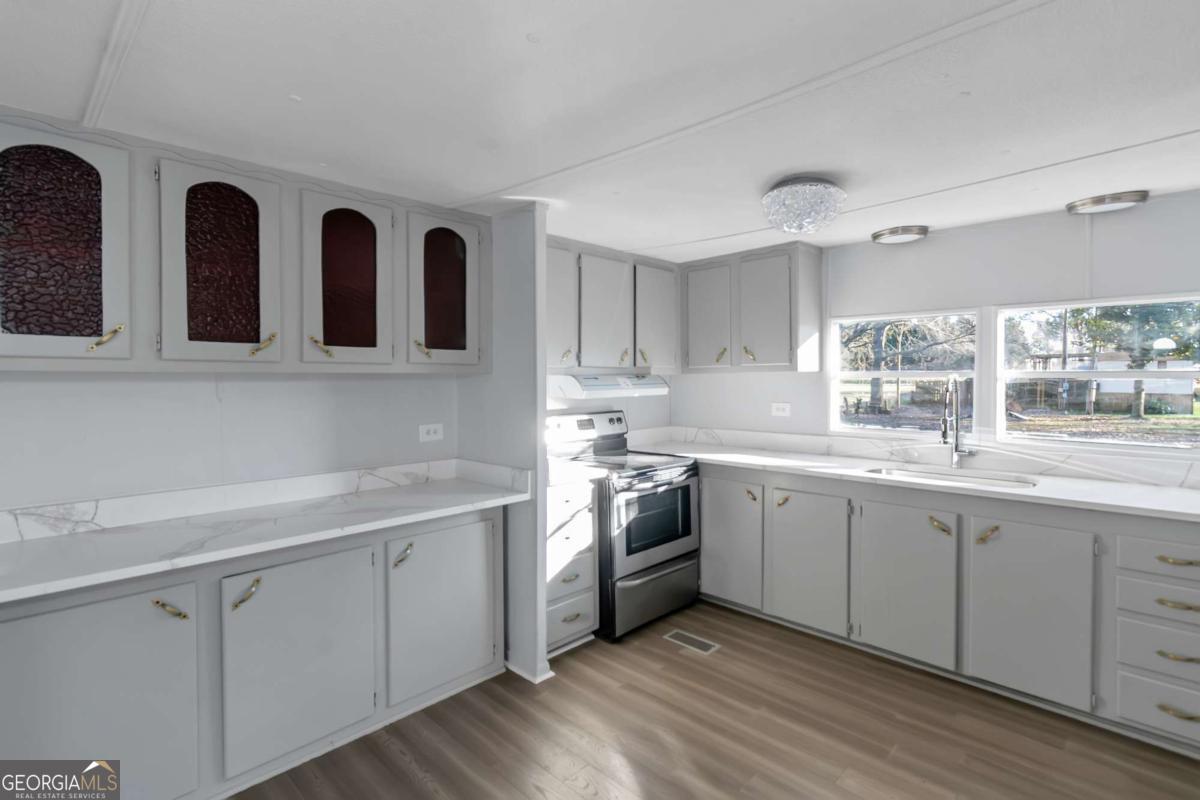 24 David Drive Hampton, GA 30228 - Photo 10 of 21 a kitchen with stainless steel appliances granite countertop a stove a sink and white cabinets